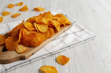 Tahta tahtada kırmızı biber aromalı patates cipsi, yan görüş. Boşluğu kopyala.