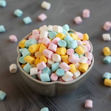 Unhealthy multi-colored mini marshmallows in a bowl, side view.