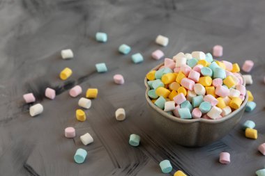 Unhealthy multi-colored mini marshmallows in a bowl, side view.