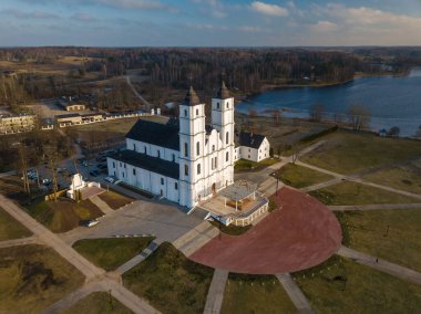 Letonya 'daki Kutsal Bakire Meryem' in Varsayımının Romalı Katolik Bazilikası 'nın insansız hava aracı görüşü. Orman ve Göl.