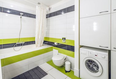 Modern dairedeki banyonun modern iç mekanı. Siyah ve yeşil fayans. Duşlu banyo. Tuvalet. Çamaşır makinesi..