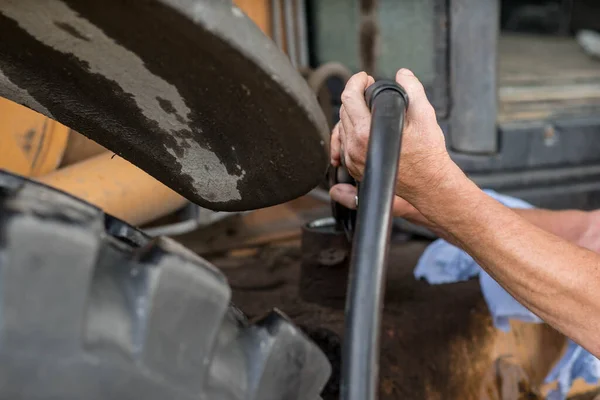 Benzin istasyonunda traktöre yakıt ikmali yapan adam. Benzin pompasıyla benzin pompalıyorum. Yakın plan..