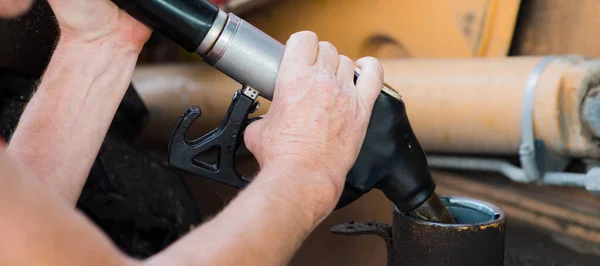 Benzin istasyonunda traktöre yakıt ikmali yapan adam. Benzin pompasıyla benzin pompalıyorum. Yakın plan..