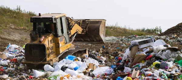 Enorme stortplaats van grote stad met ander afval. Gele trekker werkt. Voorbereiding voor recycling. — Stockfoto