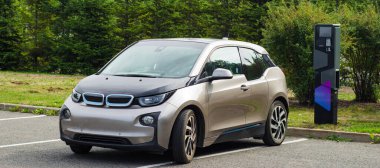 Şarj istasyonunun yakınına park edilmiş elektrikli bir araba. Çevre bakımı.