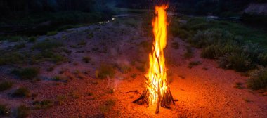 Yaz ortası Ligo kutlaması. Nehir kıyısında büyük bir şenlik ateşi. Ormanın manzaralı manzarası. Gün batımı gökyüzü. Drone görünümü.