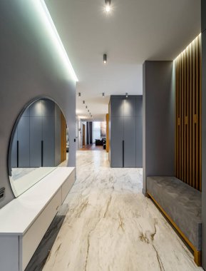 Lüks, geniş, özel evin modern interiro 'su. Gri tonlar. Giriş salonu. Oturma odası. Mermer fayans. Beyaz çekmeceler. Yuvarlak ayna.