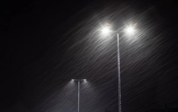 Yanan bir sokak lambasına kar yağıyor..