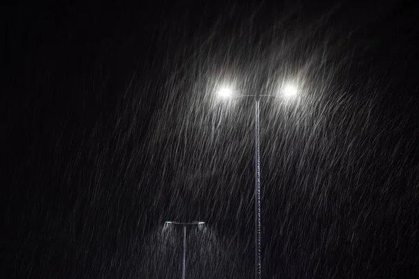 Neve che cade sullo sfondo di un lampione ardente. — Foto Stock