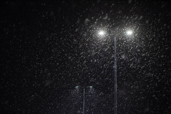 Nieve cayendo en el fondo de una lámpara de calle en llamas. —  Fotos de Stock