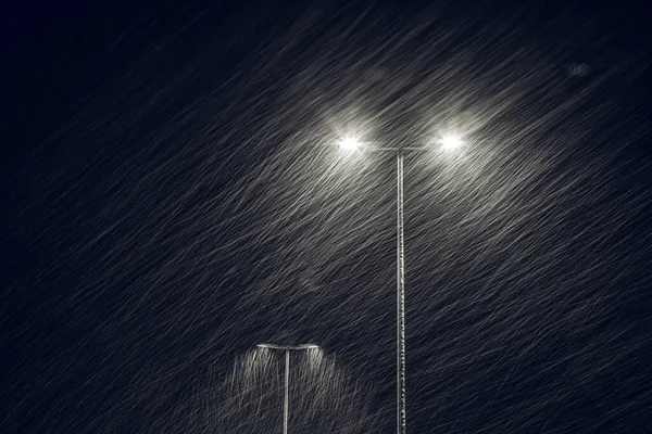 Nieve cayendo en el fondo de una lámpara de calle en llamas. —  Fotos de Stock