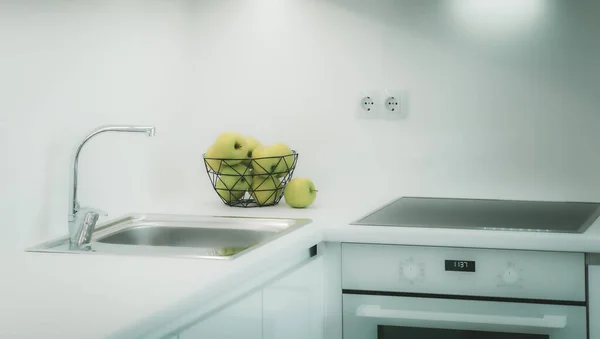 Conjunto de cozinha branca elegante. Maçãs verdes em vaso no balcão. Forno. Pia e fauce. — Fotografia de Stock