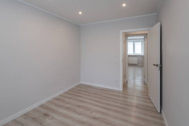 Yenilenmiş dairedeki boş odanın çağdaş iç mekanı. Beyaz duvarlar. Hafif lamine zemin. Kimse..