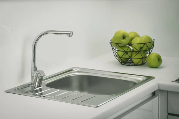 Pia de metal e torneira. Maçãs verdes em vaso. Balcão branco de conjunto de cozinha. Interior moderno. — Fotografia de Stock
