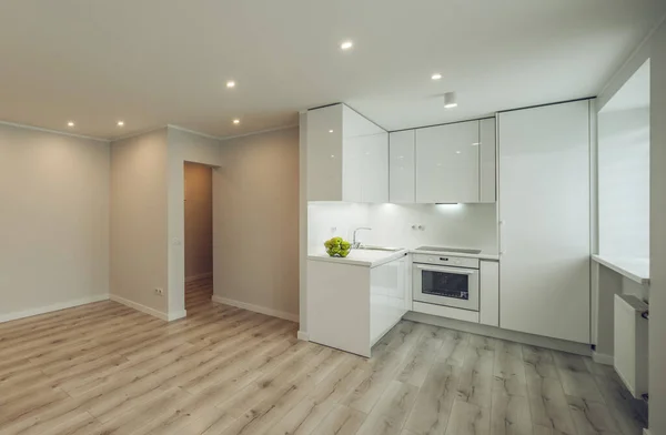 Светлый интерьер современной отремонтированной квартиры. Белая кухня с холодильником и духовкой. Паркетный пол. — стоковое фото