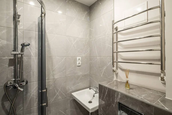 Zeitgemäße Einrichtung des Badezimmers in einer modernen Wohnung. Graue Marmorfliese. Weißes Waschbecken. Dusche. — Stockfoto