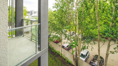 Modern konut kompleksindeki apartmanın balkonundan park manzarası.
