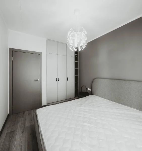 Modern iç mekan. Yatak odası dairede. Bej duvar. Yatakta yeni bir yatak — Stok fotoğraf