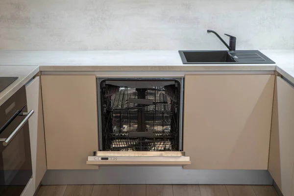 Intérieur de cuisine moderne dans des tons beiges. Évier noir. Lave-vaisselle ouvert — Photo