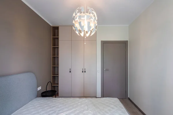Modern inredning. Sovrum i lägenhet. Beige vägg. Ny madrass på sängen — Stockfoto