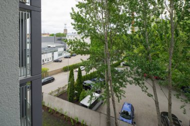 Modern konut kompleksindeki apartmanın balkonundan park manzarası.