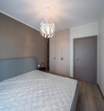 Modern iç mekan. Yatak odası dairede. Bej duvar. Yatakta yeni bir yatak