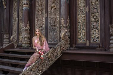 Tayland 'a seyahat eden, doğu makyajlı, parlak elbiseli güzel bir kız.