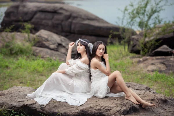 Wedding portrait of a cute bride asian woman white gorgeous wedding dress from the designer on the rock and the forest, Vintage style