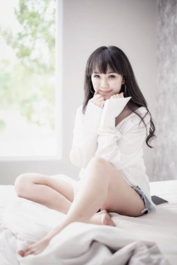 Güzel Asyalı kadın çift yatakta uyuyor. Sabah rüyası. Çekici kız rahat bir yatakta yastıkta dinleniyor..