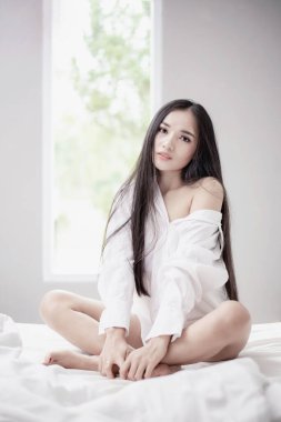 Güzel Asyalı kadın çift yatakta uyuyor. Sabah rüyası. Çekici kız rahat bir yatakta yastıkta dinleniyor..