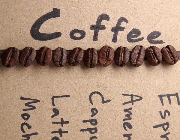 Grãos de café com papel sobre fundo textura de madeira — Fotografia de Stock