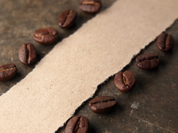 Grãos de café com papel sobre fundo textura de madeira — Fotografia de Stock