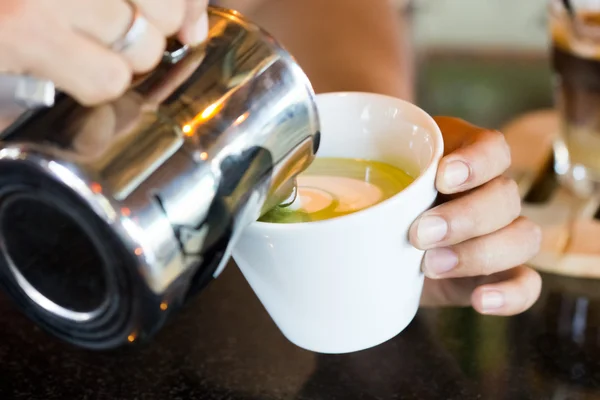 Barista hands pouring milk making hot green tea — Stock Photo, Image