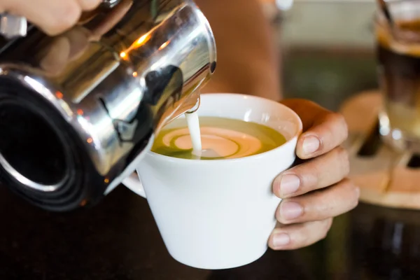 Barista hands pouring milk making hot green tea — Stock Photo, Image