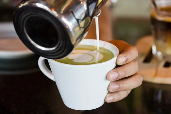 Barista hands pouring milk making hot green tea Royalty Free Stock Images