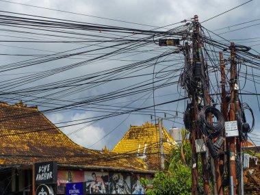 Canggu, Bali, Endonezya 'da, Ağustos 2025' te, arka planda altın kiremitli çatısı olan sütunlara bağlı bir grup siyah kablo soyut arka plan yüzeyi