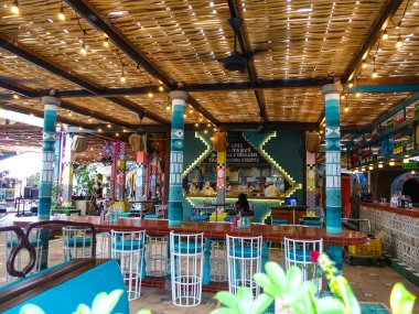 Bali 'deki barakalarda içki ve şişe sıraları sergileniyor ve içeride mutfak açacak kimlikleri belirsiz insanlar var. Bali, Endonezya, Ağustos 2025