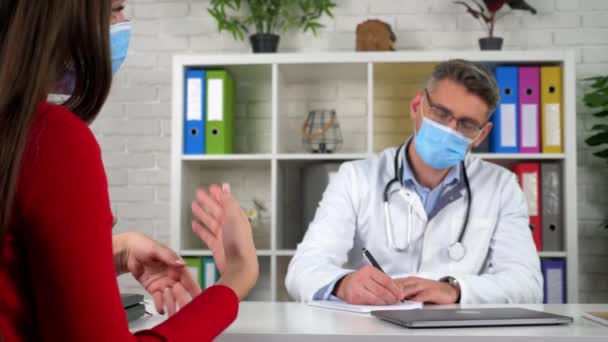Kobieta w ochronnej masce medycznej mówi o problemach zdrowotnych gesty z rąk — Wideo stockowe