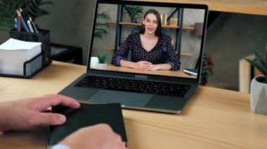 Konferans videosuyla çalışan erkek öğrenci bilgisayarına not defteri yazmış.