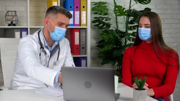 Läkare i vit medicinsk rock visar patientens orsaker till hälsoproblem på laptop — Stockvideo