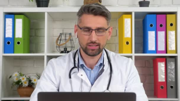 Arzt trägt weißen Arztkittel berät Patienten online Videotelefonie Laptop Webcam — Stockvideo