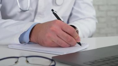 Doktor internetteki hastayı inceliyor. Bilgisayarı arıyor. Not defterine belirtiler yazıyor.