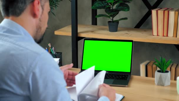 Man at home office search informacji w notebooku talk with green screen laptop — Wideo stockowe