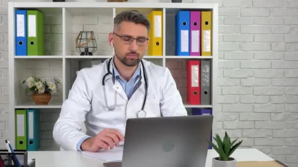 Médico remoto no casaco médico ouvir paciente vídeo on-line chamada laptop webcam — Vídeo de Stock