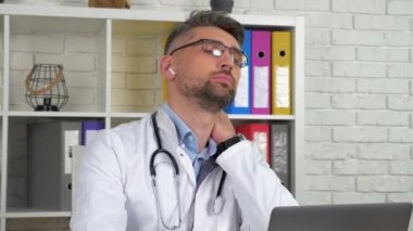 Yorgun doktor masajı uzun süre laptopta çalıştıktan sonra boyun kaslarını ovuşturuyor.