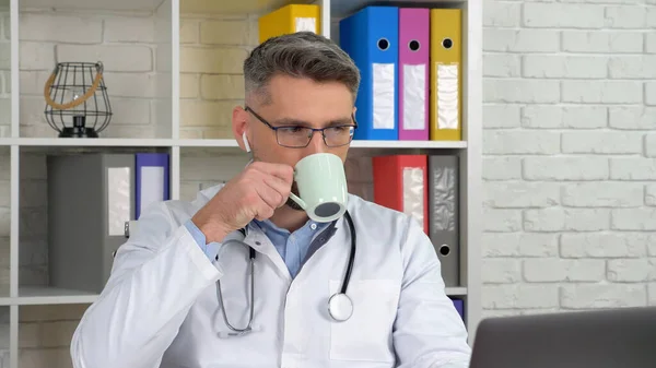 Doctor listens patient online video call laptop webcam, drinking coffee tea