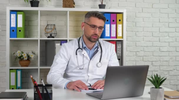 Doutor usa casaco médico branco consulta paciente chamada de vídeo on-line laptop webcam — Vídeo de Stock
