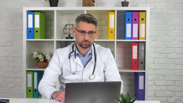 医者は白い医療コートを身に着けている患者オンラインビデオ通話ラップトップウェブカメラ — ストック動画