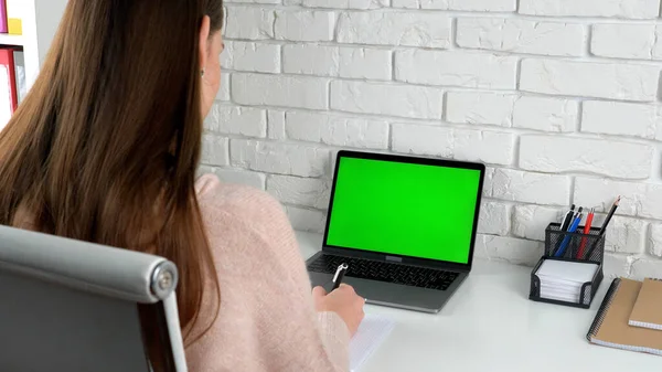 Green screen laptop woman student study writes information with pen in notebook