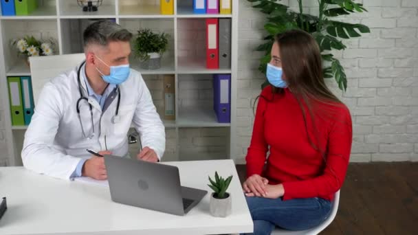 Dokter en patiënt draagt beschermende maskers op gezichten in het ziekenhuis communiceert praten — Stockvideo